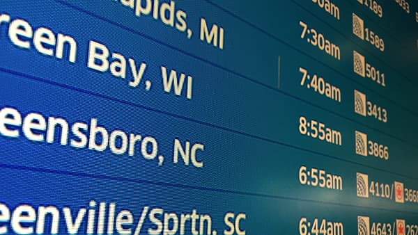 A departure board at Terminal C of Chicago O'Hare International Airport listing flights and gate numbers