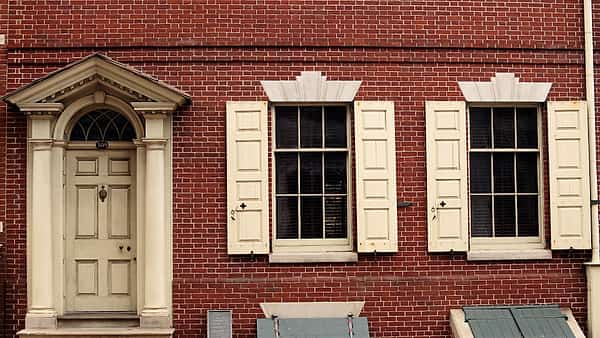 The white front door of the Bishop White House with shuttered first floor windows on either side of it