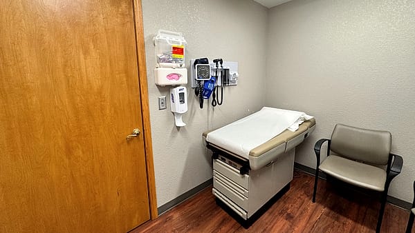 An examination room in a doctor's office, with the examination table, a chair and a wall of cabinets