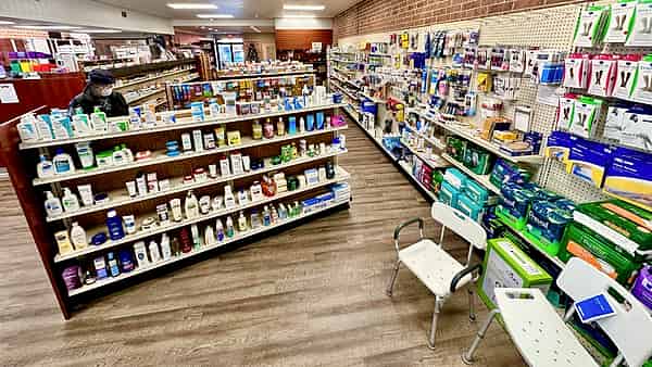 The interior of a modern pharmacy in the United States, its shelved aisles running back toward the counter