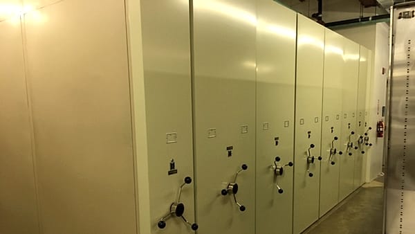 Archival records in acid-free boxes on rolling shelves at a federal conservation archive
