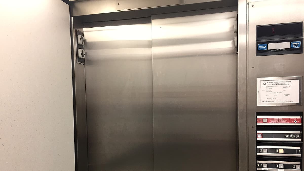 A pair of closed elevator doors in the corridor of a hospital in southern New Hampshire, with the call button beside them