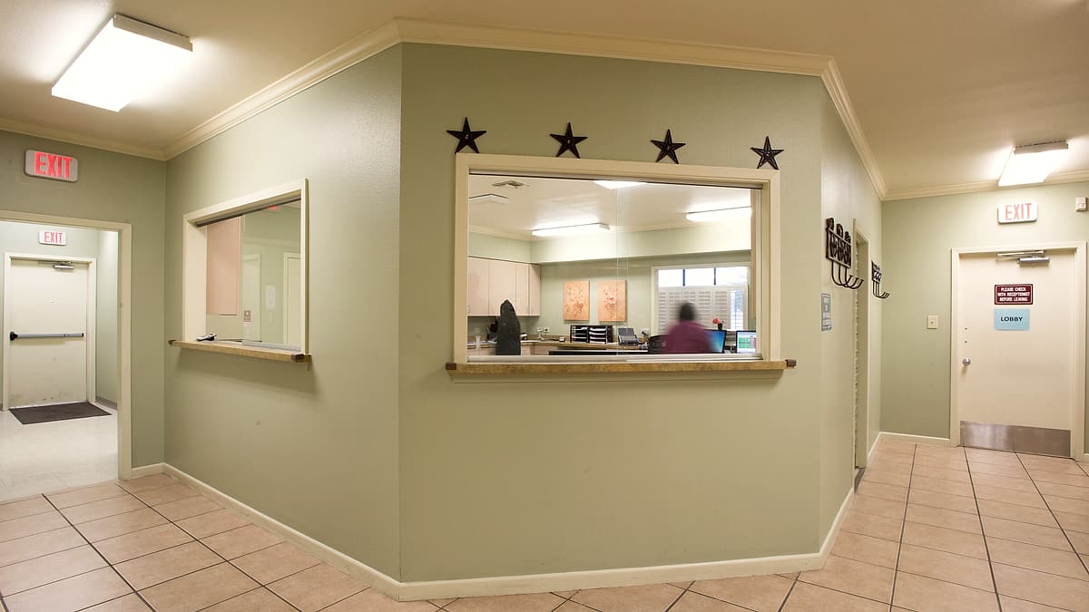 A reception counter and waiting room at the Lytle Community Health Center in Texas, screened by sliding glass panels